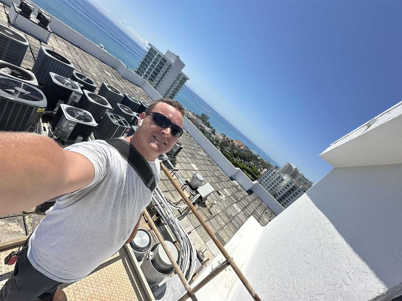 Mama's Boy technician on a rooftop job with the ocean behind